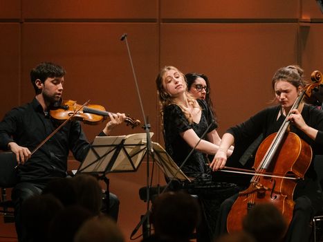 Klaviertrio mit Geiger, Cellistin und Pianist auf der Bühne