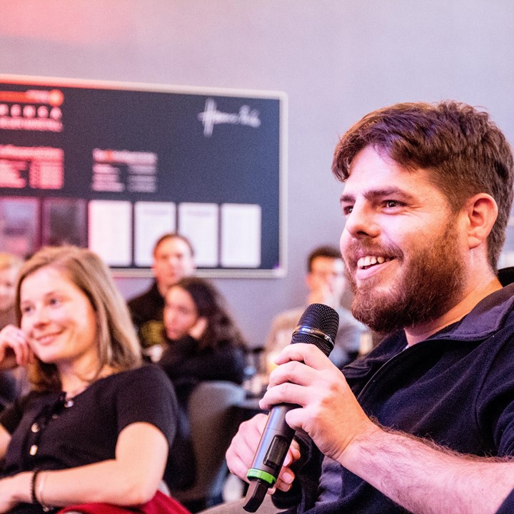 Student speaks into a microphone at the eislerlab, other students in the background